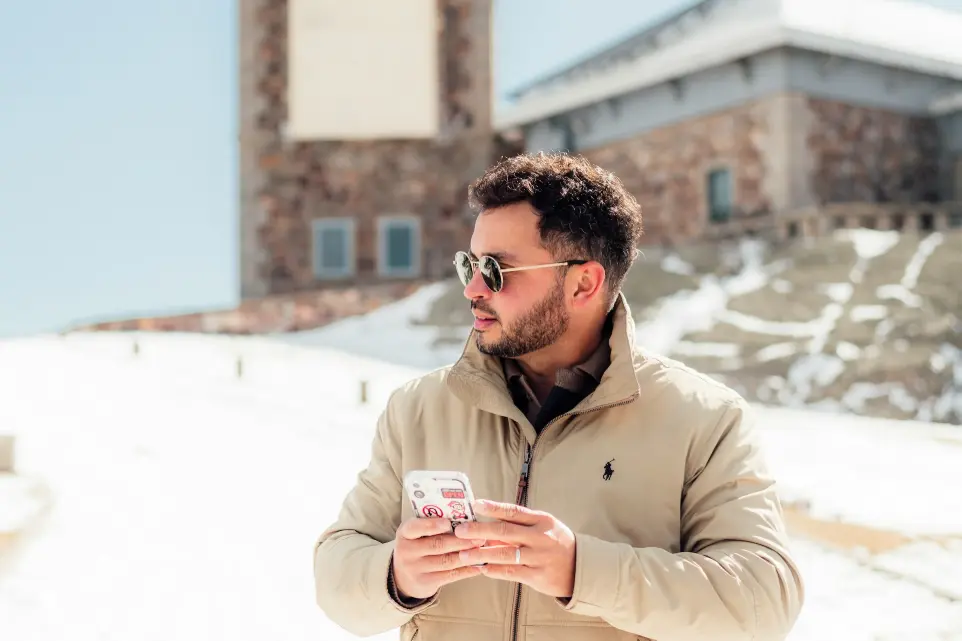 a man standing in the snow looking at his cell phone